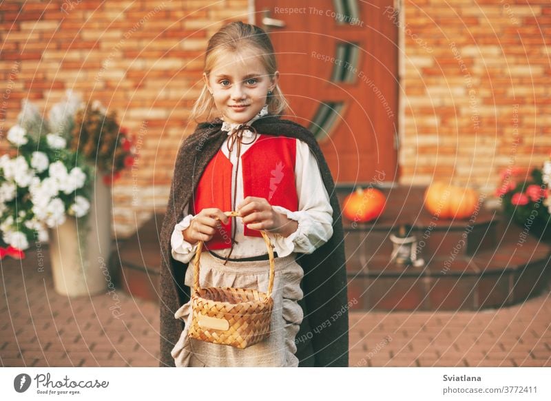Ein kleines Mädchen in einem Feenkostüm mit einem Korb in der Hand während der Halloween-Feierlichkeiten kommt zu Besuch und holt sich Leckereien zu Hause