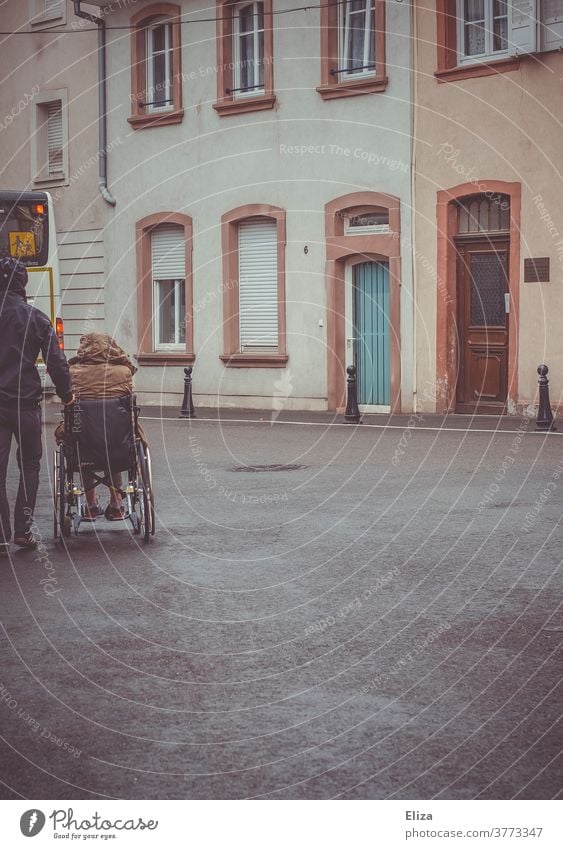 Ein Mann schiebt eine Person mit Behinderung im Rollstuhl Mobilität Handicap Gesundheitswesen Pflege Regenwetter Krankheit Ausflug schieben Gehbehinderung