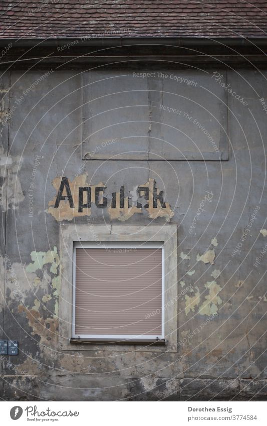 Verblasster Schriftzug - "Apotheke" an Hauswand Verfall Gebäude alt kaputt Mauer Fassade Fenster Vergänglichkeit Farbfoto Gedeckte Farben Außenaufnahme grau