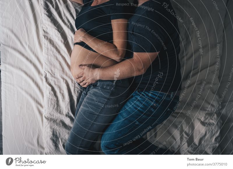 Liebespaar auf dem Bett - Er hält den Bauch seiner schwangeren Frau schwangerschaftsshooting Paar Erwachsene Babybauch Badewanne Mutter Photo-Shooting Farbfoto