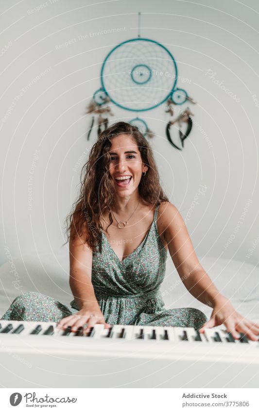 Lächelnde Frau spielt Klavier im Wohnzimmer spielen Musik Musiker Probe Talent Fähigkeit kreativ Melodie ethnisch modern Appartement Gesang ausführen Klang