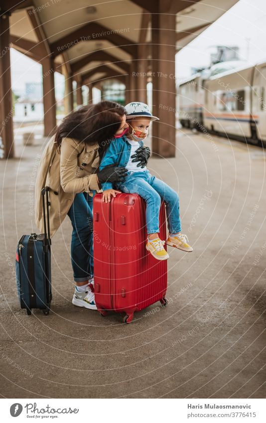 Mutter und Kind mit Gesichtsmaske und Gepäcktaschen warten am Bahnhof Erwachsener Tasche Taschen schön Kaukasier Großstadt Corona-Virus Covid-Reisen covid-19