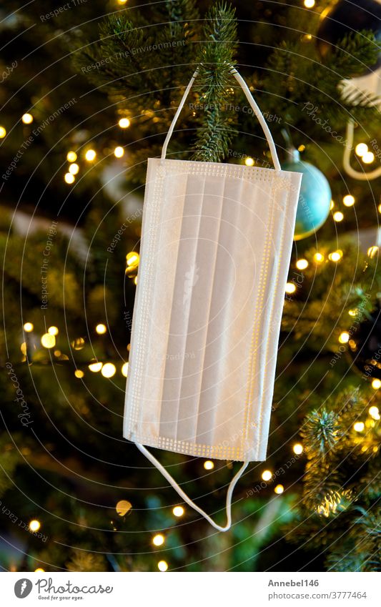 Weihnachtsbaum mit Coronavirus-Gesichtsmaske im Baum hängend, geschmückt mit Covid-19-Sicherheitsmaske und Weihnachtskugeln für strahlende Weihnachten Feier