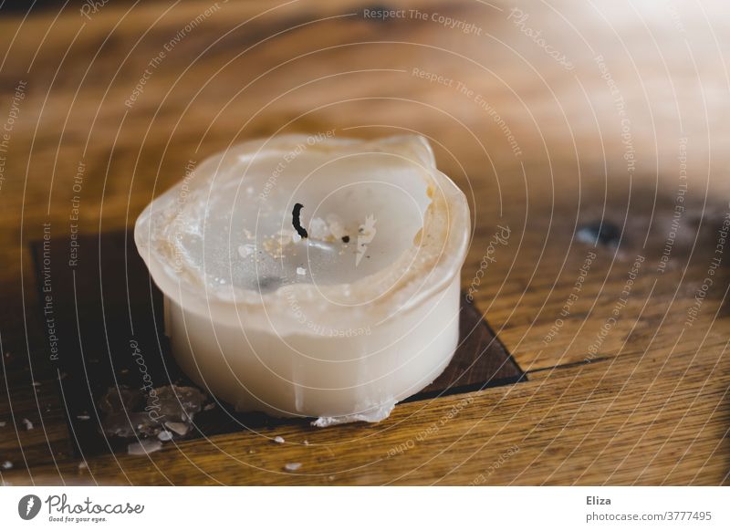 Ein Kerzenstumpen auf einem Holztisch kerzenstumpen abgebrannt aus Wachs weiß ausgebrannt erloschen