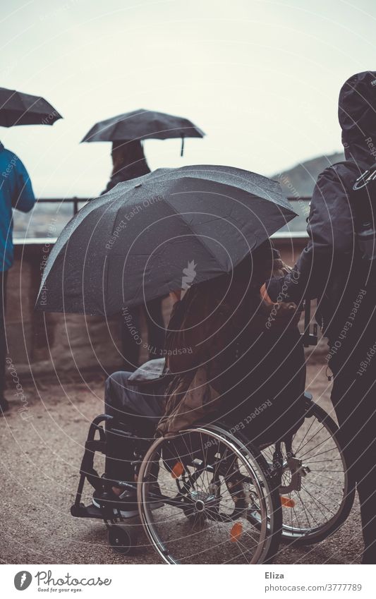 Ausflug mit Rollstuhl und Regenschirm weil es regnet und schlechtes Wetter ist. barierrefrei Aussicht Sightseeing Herbst nass Aussichtspunkt kalt regnerisch