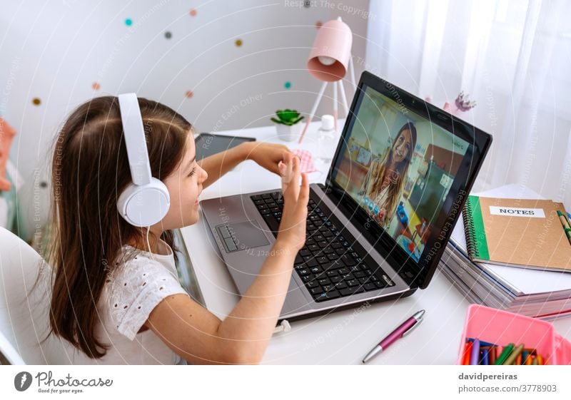 Mädchen beobachtet Online-Klasse ihrer Lehrerin Heimunterricht Laptop winkend Online-Kurse digitale Weisheit Videokonferenz Videoanruf studierend Kopfhörer