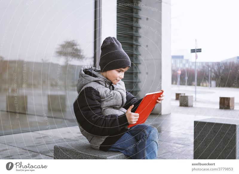 7-jähriger Junge spielt im Winter Online-Spiel auf Tablet-Computer im Freien Kind Tablet Computer spielen Technik & Technologie digital jung Spaß Internet