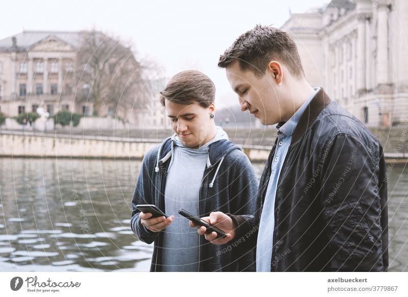 zwei smartphonesüchtige männliche Teenager stehen zusammen und schauen auf Handy Smartphone Abhängig Telefon unsozial jung Männer Freunde Technik & Technologie