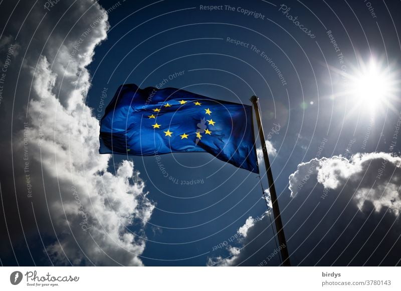Europaflagge im Gegenlicht weht im Wind, dramatische Wolkenkulisse und Sonne.Europa Europafahne Dynamik wehen martialisch blau gelb leuchten durchscheinend