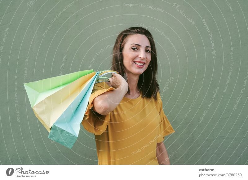 Lächelnde junge Frau, die eine Einkaufstasche hält Junge Frau kaufen Frau beim Einkaufen Einkaufstaschen Werkstatt Käufer Mädchen Spaß lustig Kaufhaus Gewerbe
