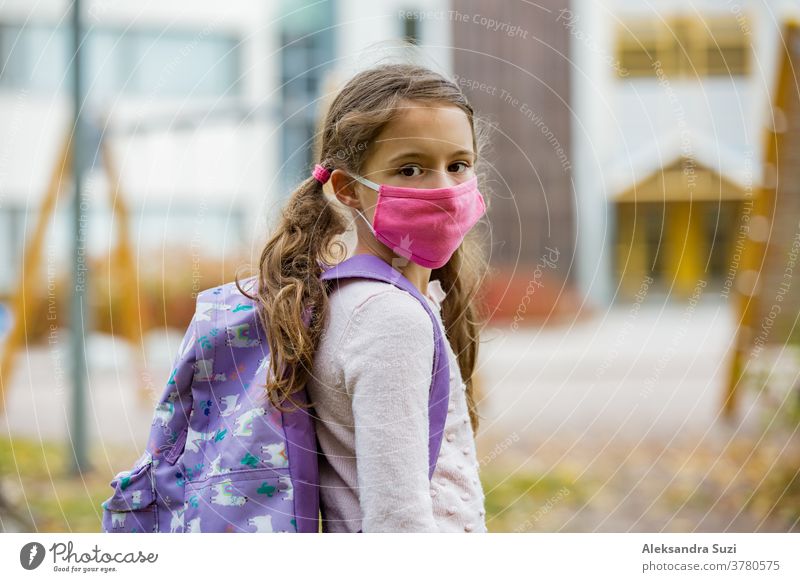 Schulmädchen mit wiederverwendbarer Schutzmaske aus Stoff beim Schulbesuch. Schulbildung während der Coronavirus-Pandemie. Sicherheitsmaßnahmen und soziale Distanzierung