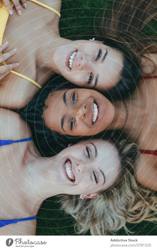 Glückliche multirassische Frauen liegen zusammen auf Gras Lügen Zusammensein Angesicht zu Angesicht Freundschaft sorgenfrei jung freundlich Freiheit