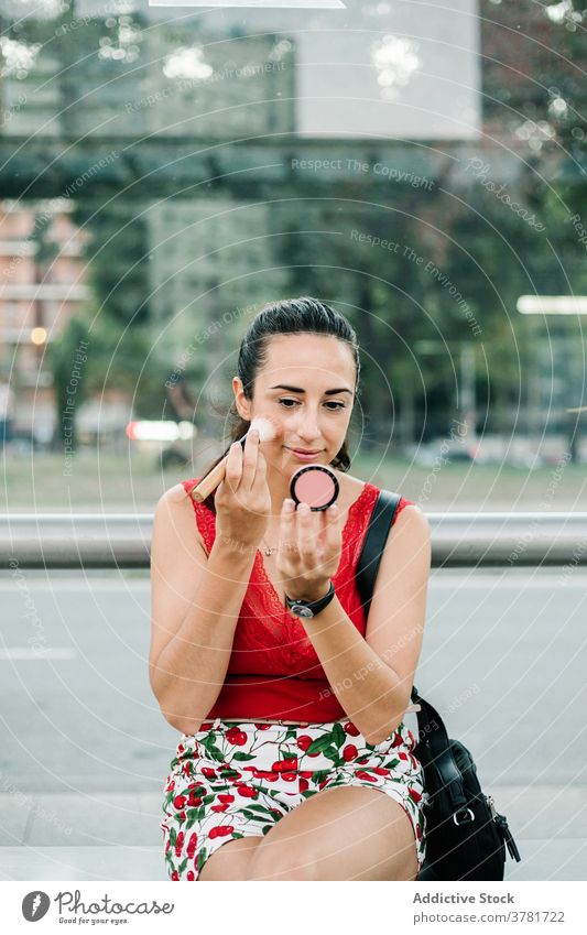 Junge Frau mit Spiegel Anwendung erröten auf der Straße Make-up bewerben Schönheit Kosmetik urban modern jung brünett Glamour Stil Mode Lifestyle Zeitgenosse
