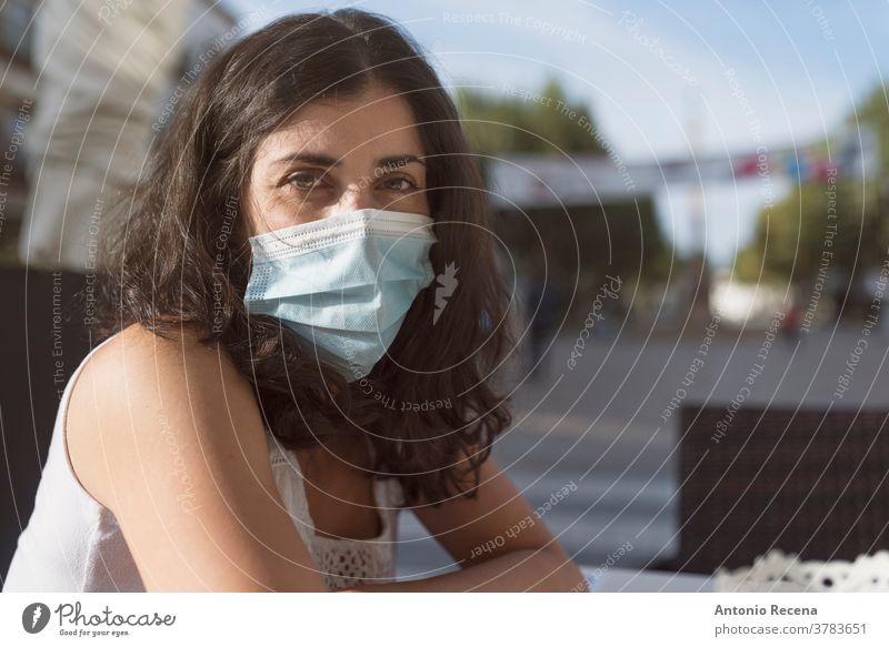 Hübsche Frau in Bar-Terrasse mit Gesichtsmaske, die in die Kamera schaut Mundschutz covid-19 Coronavirus Verschmutzung Allergie chirurgisch Person Menschen