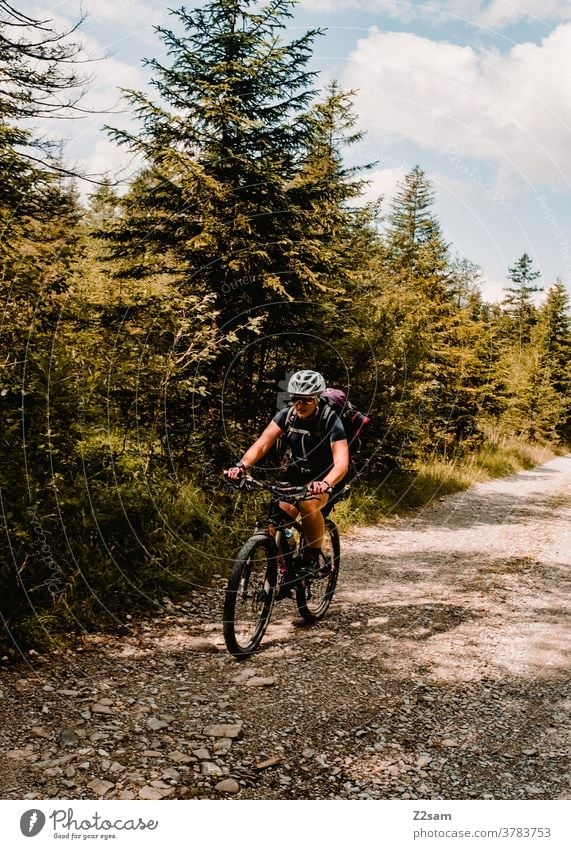 Junge Frau fährt mit MTB auf einem Waldweg mountainbike mtb fahrrad abenteuer steine wald alpen berge natur landschaft einsam sportlich rucksack reisen urlaub