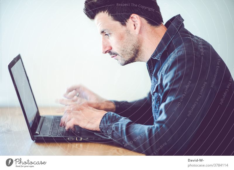 Mann tippt mit schnellen Fingern auf seinem Laptop herum tippen Geschwindigkeit konzentriert arbeiten Schreibtisch Homeoffice hektisch zeitdruck Erfolg