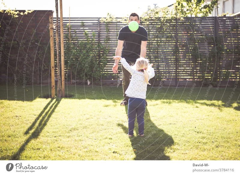 Vater und Kind spielen zusammen mit dem Ball Garten Zusammensein Frühling Sommer Zeit Familienzeit gemeinsam Tochter