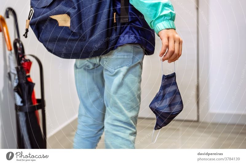 Unbekannter Junge mit Rucksack, der eine Maske in der Hand hält unkenntlich Beteiligung Mundschutz Coronavirus zur Schule gehen covid-19 Virus Kind