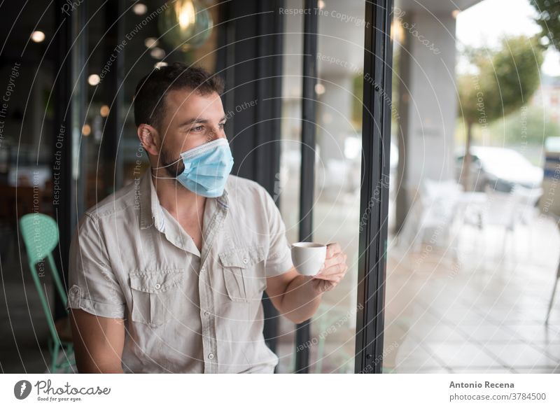 Mann mit chirurgischer Maske trinkt Kaffee und schaut aus dem Fenster Mundschutz Gesicht covid-19 Coronavirus Verschmutzung Allergie Person Menschen eine Person