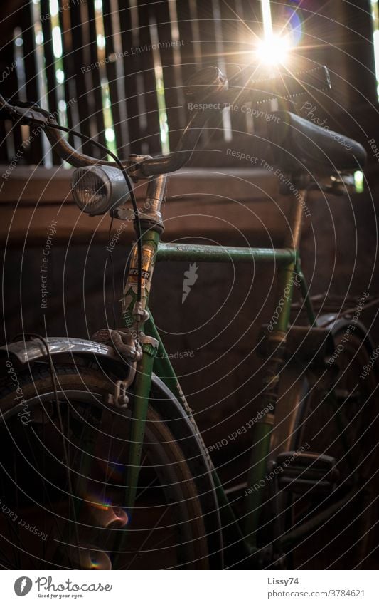 Altes, grünes Herren-Fahrrad auf dem Scheunenboden, angestrahlt durch die von außen, zwischen den Holzbrettern eindringenden Sonnenstrahlen Herrenfahrrad Retro