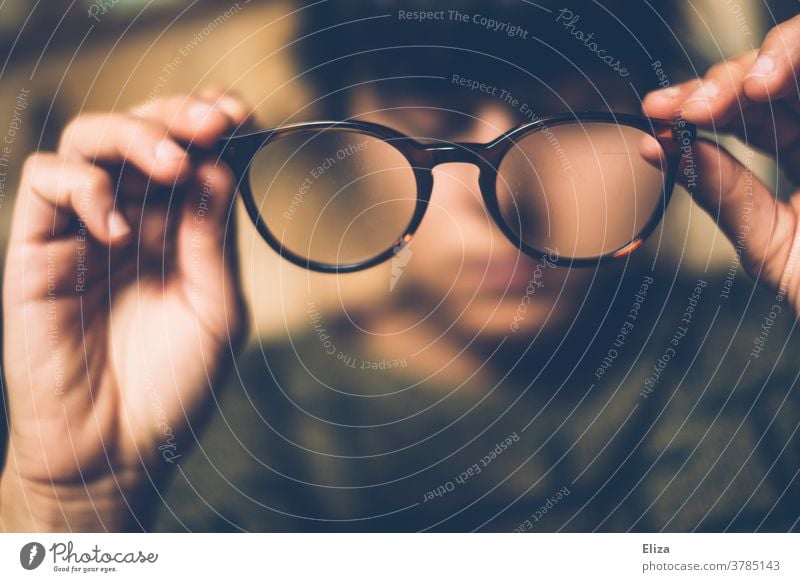 Eine Frau nimmt ihre Brille ab Durchblick beobachten betrachten abnehmen Brillenträger unscharf Sehvermögen Sehschwäche