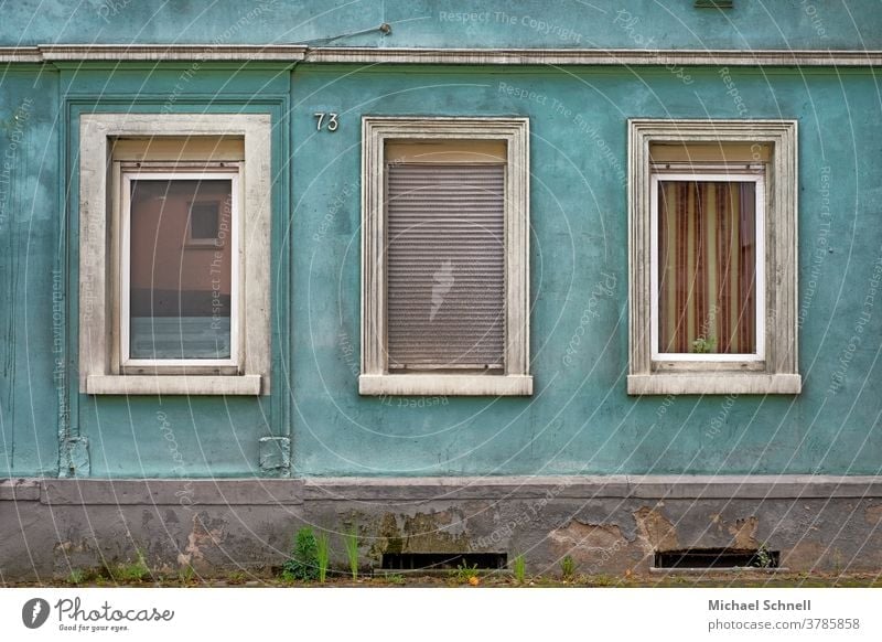 Triste Hauswand eines alten Hauses mit drei Fenstern, eines davon mit geschlossenen Rolladen Wand Fassade Mauer Menschenleer Außenaufnahme Farbfoto Gebäude Tag