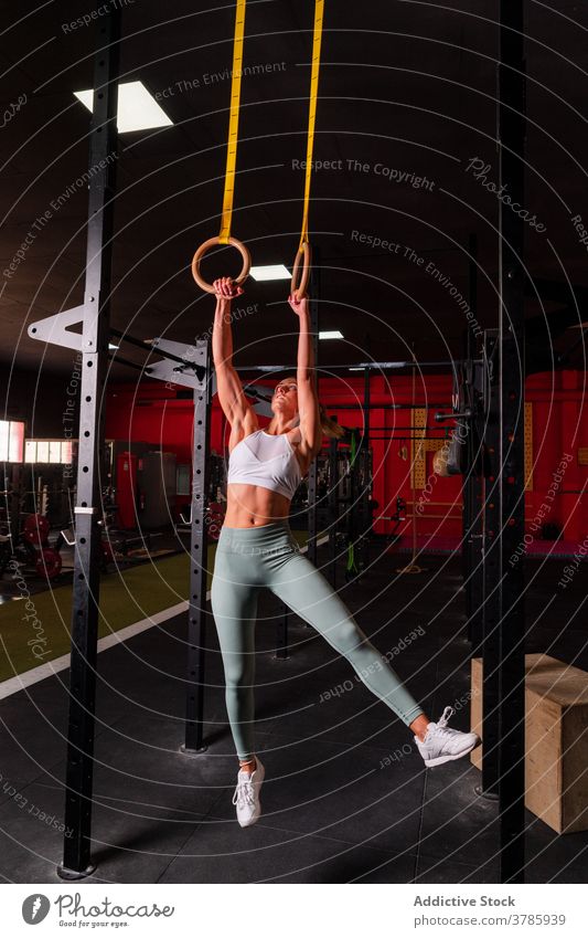 Ausdauersportlerin bei Übungen an Gymnastikringen gymnastisch Ring Training Bauchmuskeln Frau Gleichgewicht stark anstrengen Unterleib calisthenics Fitness