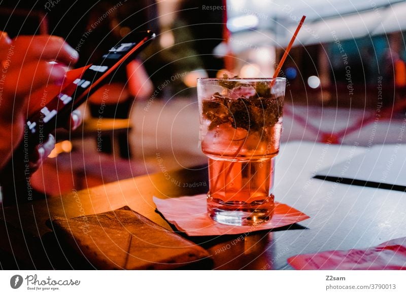 Junge Frau mit Smartphone und Cocktail in einer Bar gardasee Urlaub trinken getränk ausgehen Alkohol warten verabredet Cocktailbar Glas Getränk