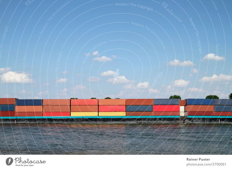 Frachtschiff mit zahlreichen bunten Containern auf einem Fluss blau Business Ladung wirtschaftlich Kranich Versand Dock Export Ware hafen importieren