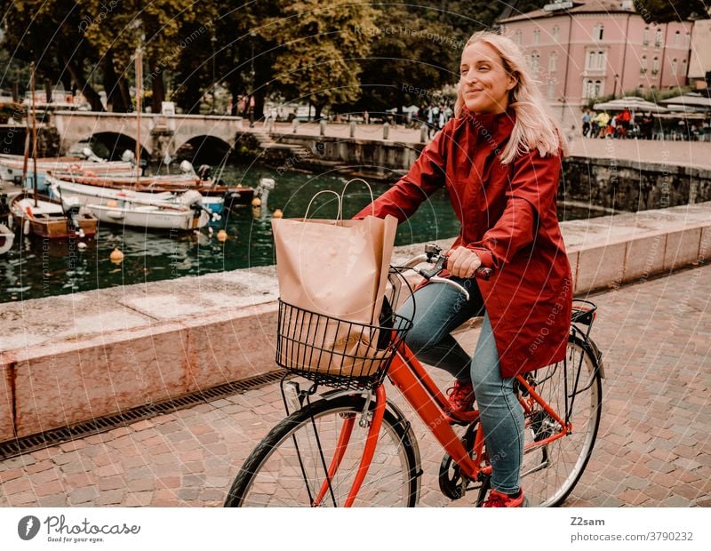 Junge Frau fährt mit dem Fahrrad durch Riva del Garda gardasee norditalien bombig Stadt mobilität Bewegung kaufen einkaufen italienisch Hafen Regeneration