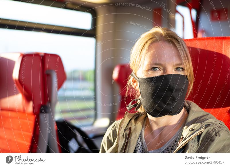 Frau, die in einem Eisenbahnzug reist und eine selbst angefertigte Gesichtsmaske trägt. Coronavirus und Reisekonzept Mundschutz U-Bahn reisen tragend Korona