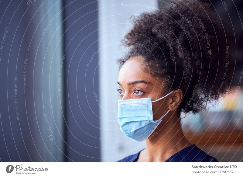 Weibliche Ärztin mit Gesichtsmaske und Kittel unter Druck im geschäftigen Krankenhaus während einer Gesundheitspandemie Arzt Krankenpfleger bürstet