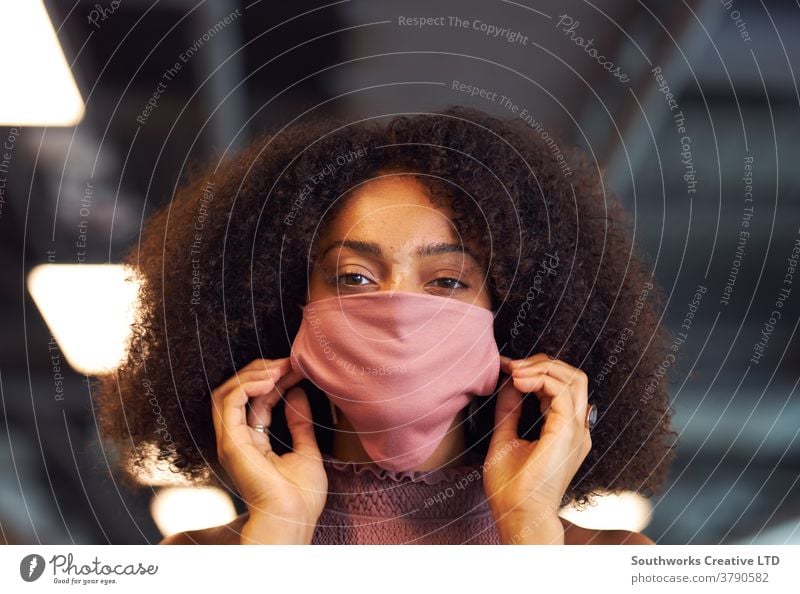 Porträt einer Geschäftsfrau, die während der Covid-19-Pandemie eine Gesichtsmaske in einem modernen Großraumbüro aufsetzt Business Gesichtsbedeckung ppe