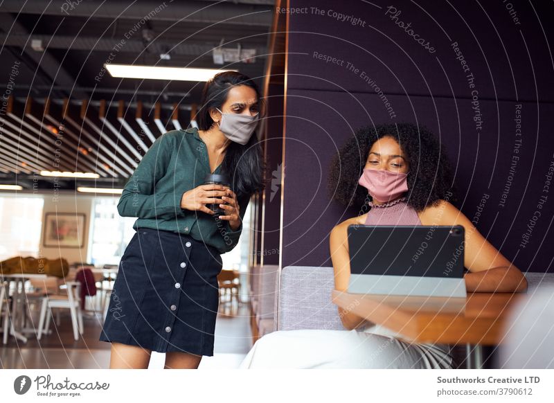 Geschäftsfrauen mit Masken, die während einer Gesundheitspandemie sozial distanzierte Treffen im Amt haben Business Sitzung Gesichtsmaske Gesichtsbedeckung ppe