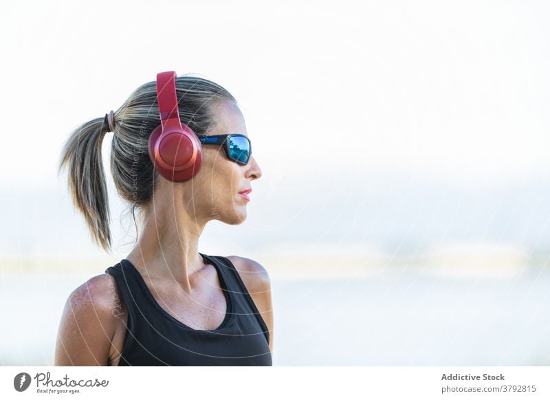 Frau mit Kopfhörern vor dem Training im Park Sportlerin zuhören Fitness Musik schlank Vitalität Athlet passen Aktivität sportlich Sportkleidung Sportbekleidung