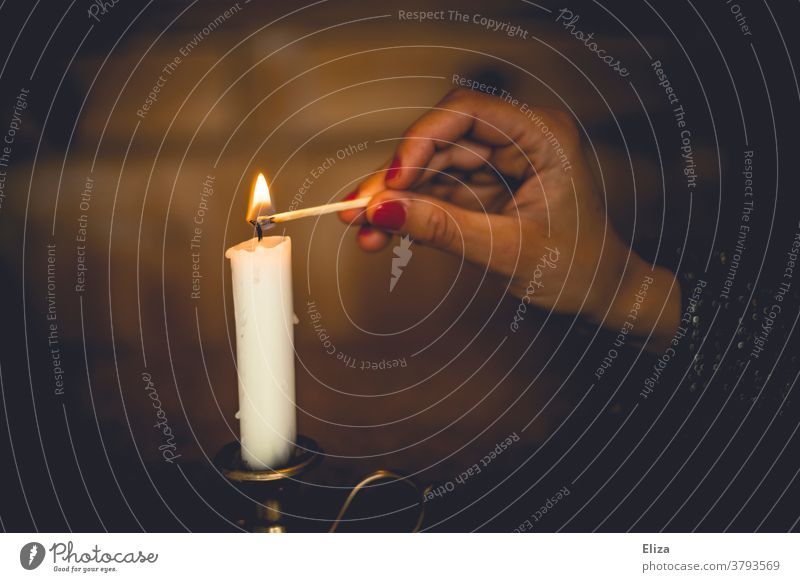 Eine Frau zündet zuhause eine weiße Kerze mit einem Streichholz an anzünden gemütlich Kerzenschein Romantik brennen stimmungsvoll Wärme Licht