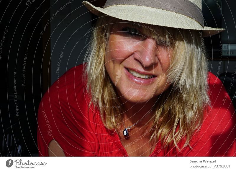 Frau mit Hut im Sonnenlicht blonde Haare lowlight hoheblende lachen Zähne
