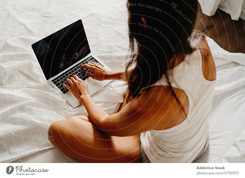 Anonyme Frau mit Laptop im Bett Morgen benutzend Browsen Schlafzimmer heimwärts jung Gerät Apparatur Internet gemütlich online Freude wach Kommunizieren