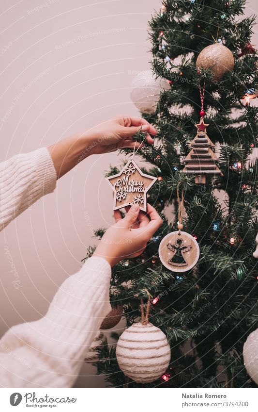 Eine Person schmückt den Weihnachtsbaum. Die Person hängt einen Weihnachtsstern mit einem Weihnachtsgruß auf. Nahaufnahme. Weihnachten dekorativ Feier