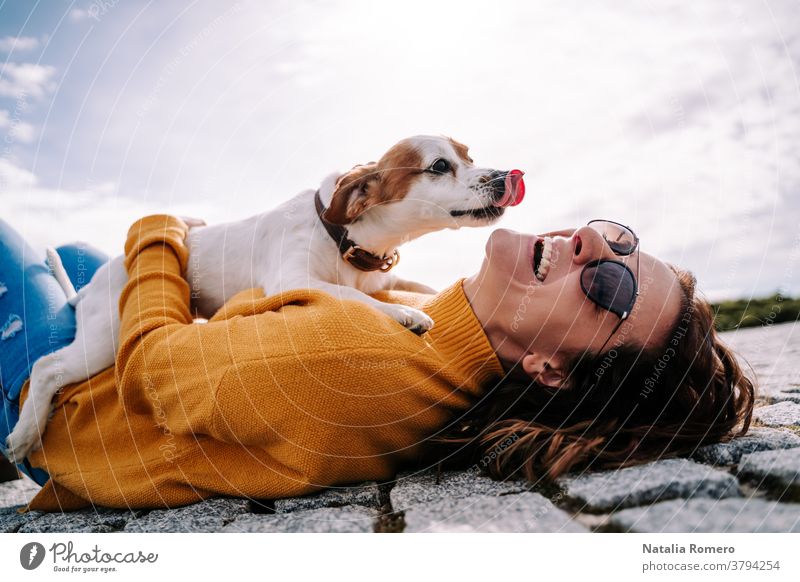 Eine schöne Frau lacht, während ihr Haustier an einem sonnigen Tag im Park von Madrid ihr Gesicht leckt. Der Hund ist auf seinem Besitzer zwischen ihren Händen. Lebensstil eines Familienhundes im Freien