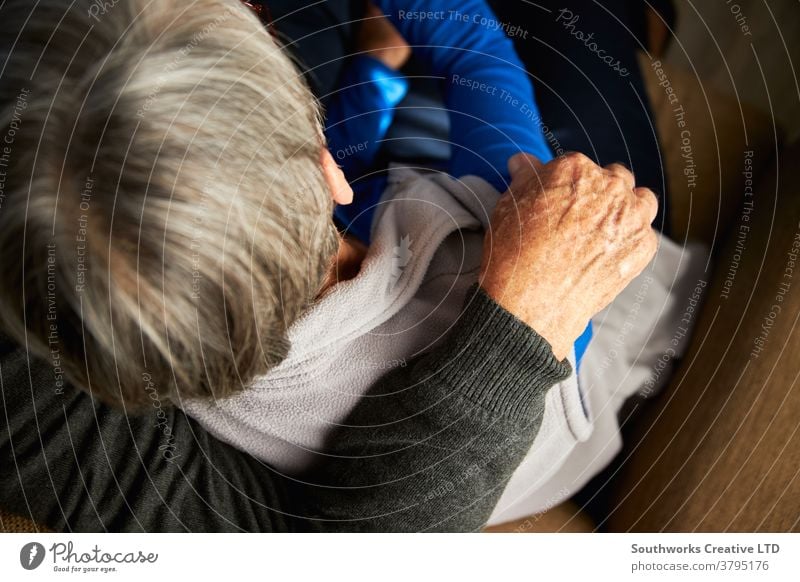 Nahaufnahme Rückansicht eines liebenden älteren Paares zu Hause, das sich gemeinsam auf dem Sofa umarmt Senior Senioren liebevoll umarmend Zuneigung anhänglich