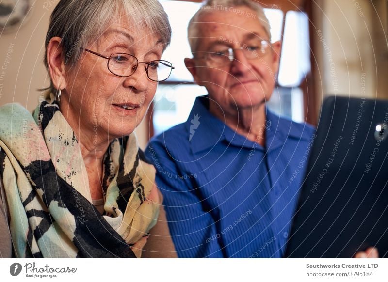 Älteres Ehepaar zu Hause macht einen Videoanruf an die Familie oder schaut sich einen Film auf einem digitalen Tablet an Paar Senior Senioren Video-Chat