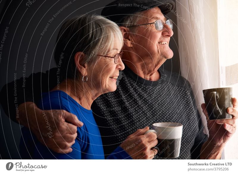 Liebende Seniorenpaare entspannen sich und plaudern am Fenster zu Hause zusammen mit einem heissen Getränk Paar in den Ruhestand getreten entspannend Stehen