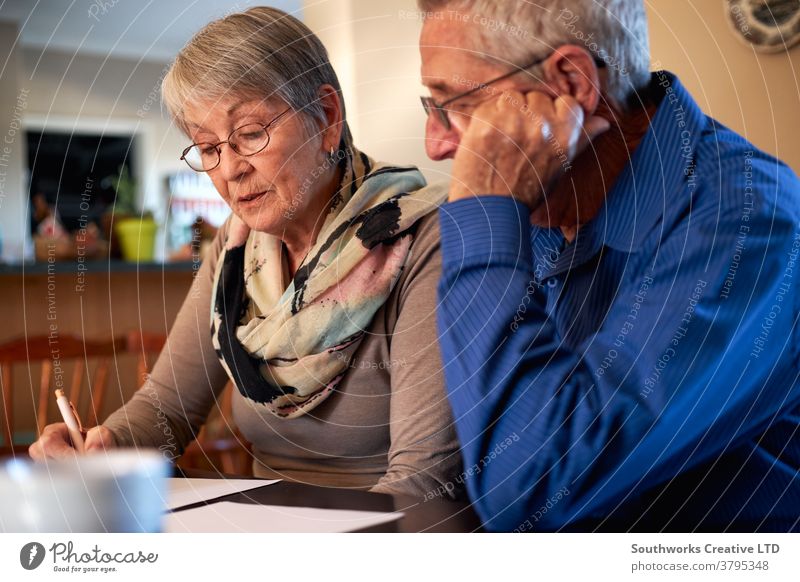 Älteres Ehepaar zu Hause am Tisch sitzen und persönliche Finanzen überprüfen Paar Senior Senioren in den Ruhestand getreten kaufen auserwählend Überprüfung