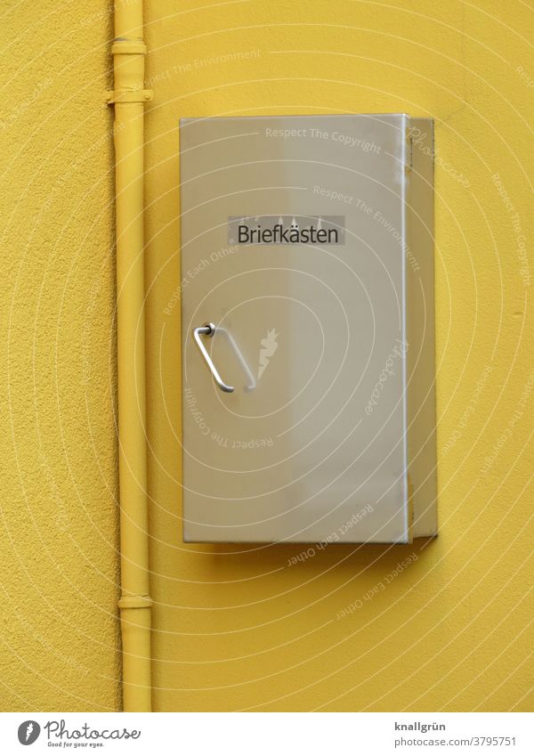 Silberfarbener Briefkasten auf einer gelben Hauswand mit gelbem Fallrohr Kasten Aufbewahrung Post Außenaufnahme Metall Tag Farbfoto Menschenleer Wand Mauer
