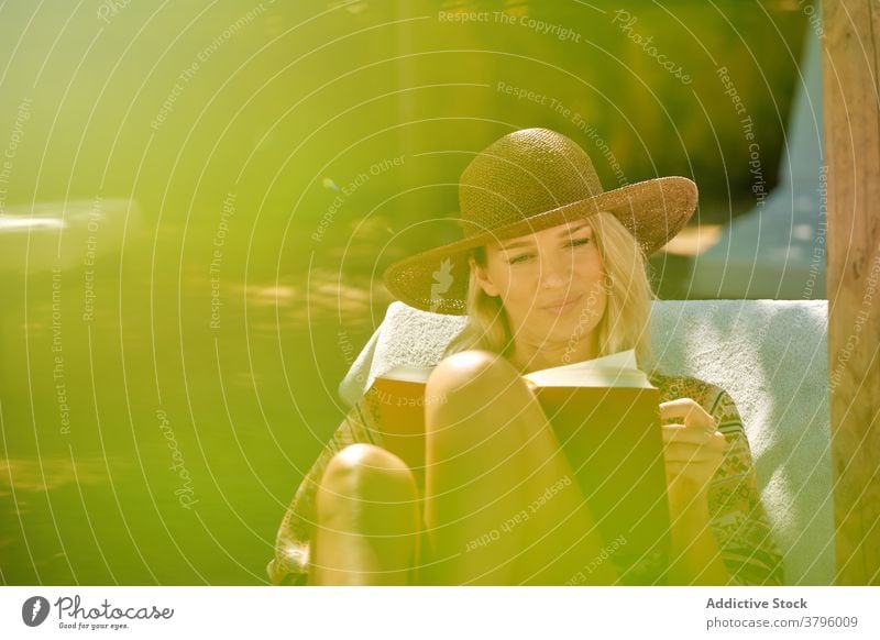 Fröhliche weibliche Touristin liest ein Buch, während sie sich auf einem Liegestuhl ausruht Frau lesen ruhen Kälte Zahnfarbenes Lächeln schön reisen Glück