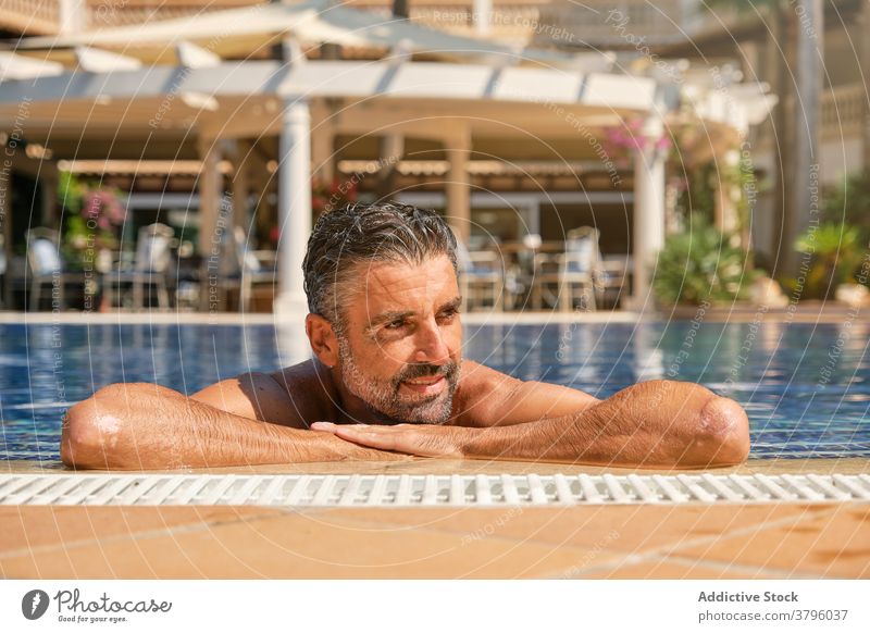 Entspannter Mann beim Chillen im Schwimmbad im Resort Pool Sommer Glück genießen Kälte reisen sich[Akk] entspannen Beckenrand Urlaub männlich Vollbart ethnisch