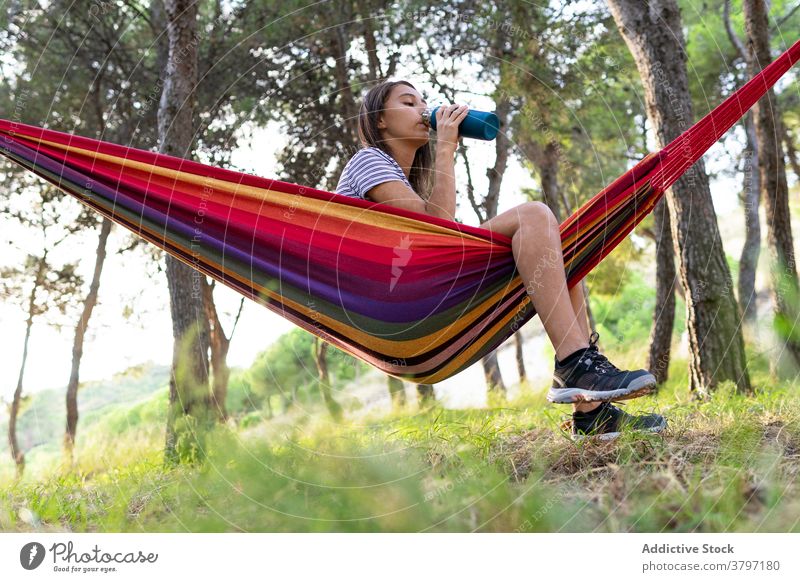 Ruhige Frau trinkt Wasser in der Hängematte Durst trinken Hydrat Park Flasche Erfrischung hängen Sommer Getränk genießen ruhen sich[Akk] entspannen Erholung