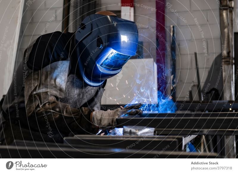 Professioneller Schweißer mit Schutzhelm in der Werkstatt Schweißnaht Metall Mann Maschine dunkel Funken Licht männlich Arbeiter Beruf professionell Werkzeug