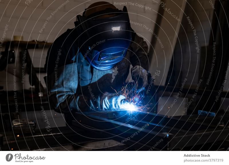 Professioneller Schweißer mit Schutzhelm in der Werkstatt Schweißnaht Metall Mann Maschine dunkel Funken Licht männlich Arbeiter Beruf professionell Werkzeug